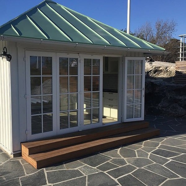 Vikdörr i pvc i litet vitt gästhus med grönt plåttak